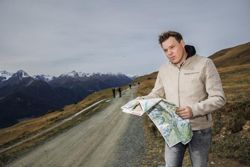 Sven Berchtold mit einer Landkarte auf einem Wanderweg.